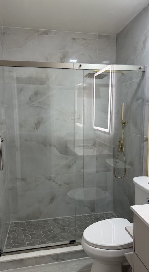 Baño remodelado con ducha de cristal y azulejos grises