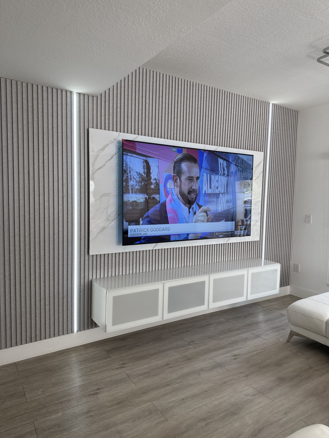 Pared de TV con listones, luces LED y gabinete blanco